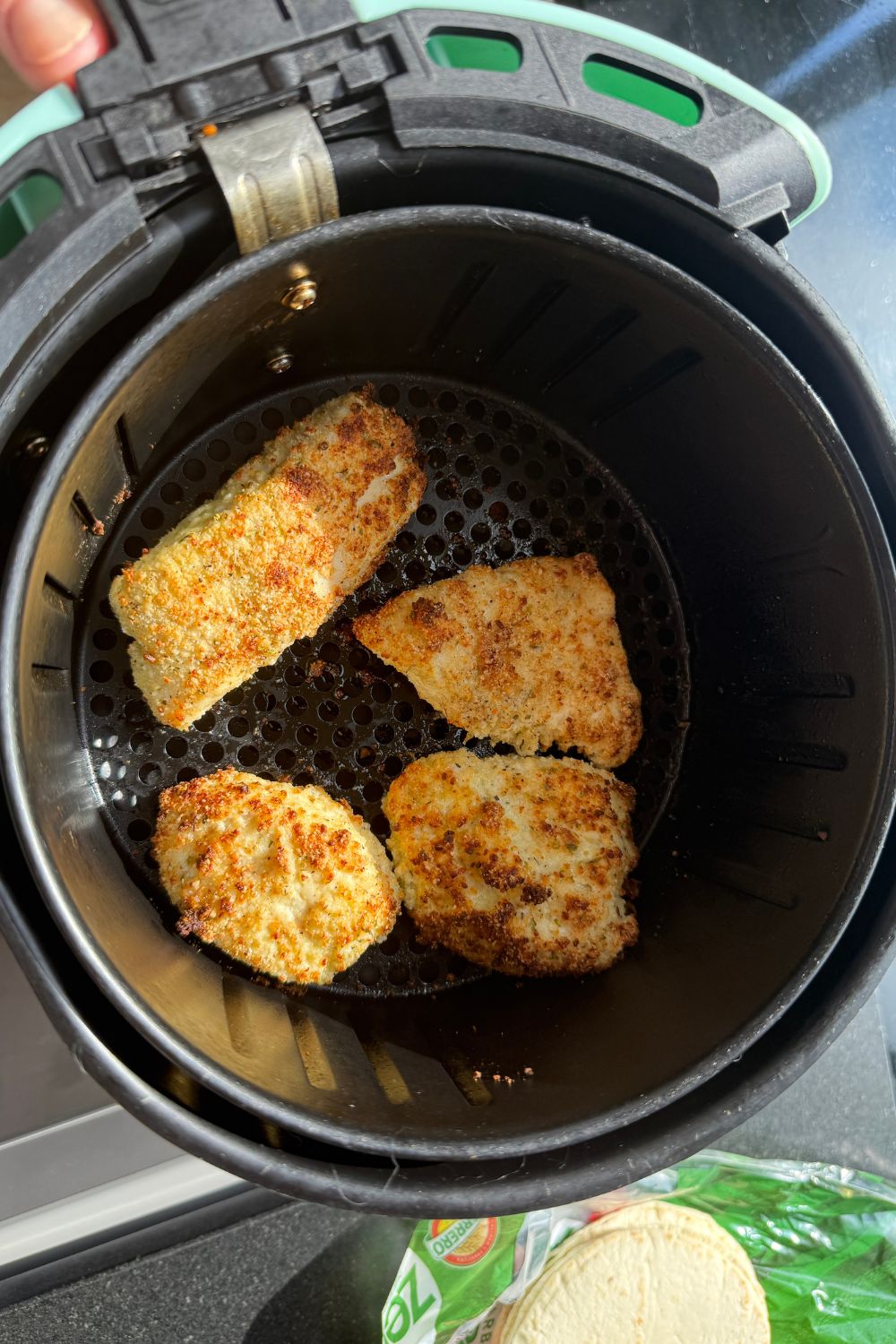 breaded chicken cooking in an air fryer basket